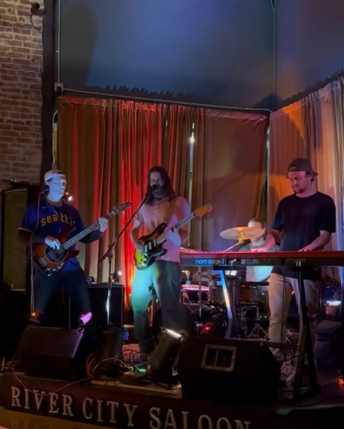 The West Goats performing live at River City Saloon, a warm indoor bar venue with red curtains